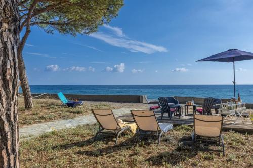 eine Gruppe von Stühlen und einem Sonnenschirm am Strand in der Unterkunft Villa Les 3 frères in San-Nicolao