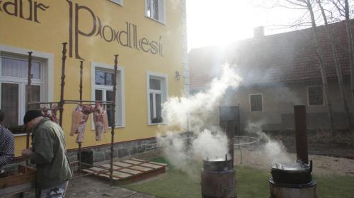 a man cooking food in front of a building at Penzion Pivovar Podlesí in Příbram