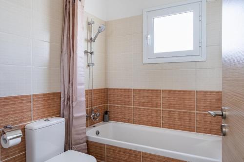 a bathroom with a toilet and a tub and a window at Phoenix 2-Bedroom Apartment in Larnaca