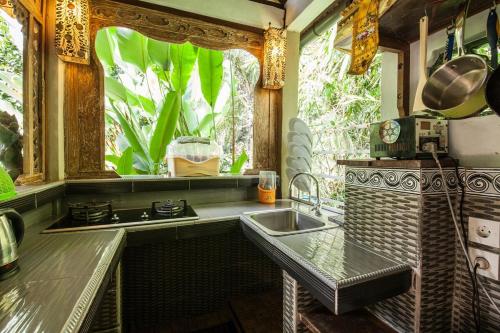 a kitchen with a sink and a stove and a window at Secluded jungle villa w private pool & serene view in Ubud