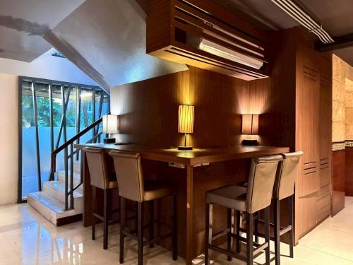 a kitchen with a wooden bar with stools at ลีลาวดี รามอินทรา - Leelawadee Resotel Raminthra 23 in Bangkok