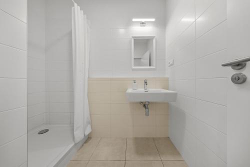 a white bathroom with a sink and a shower at Air conditioned 1 room apartment with parking, new building, Ružinov in Trnávka