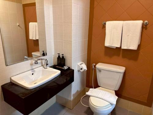 een badkamer met een wastafel, een toilet en een spiegel bij ลีลาวดี รามอินทรา - Leelawadee Resotel Raminthra 23 in Bangkok