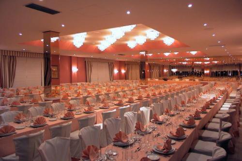 un gran salón de banquetes con mesas blancas y sillas blancas en MLC Benavente en Benavente