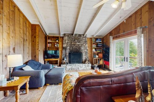 a living room with a couch and a stone fireplace at Tree Top Cabin in Beech Mountain