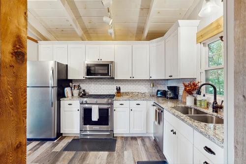 a kitchen with white cabinets and a stainless steel refrigerator at Tree Top Cabin in Beech Mountain