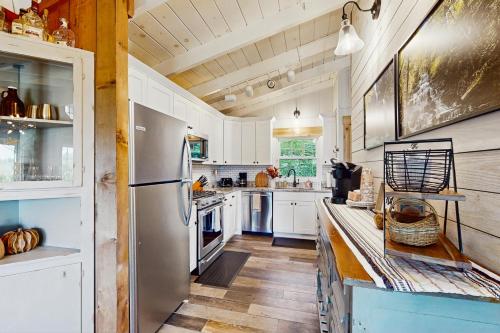 a kitchen with white cabinets and a stainless steel refrigerator at Tree Top Cabin in Beech Mountain