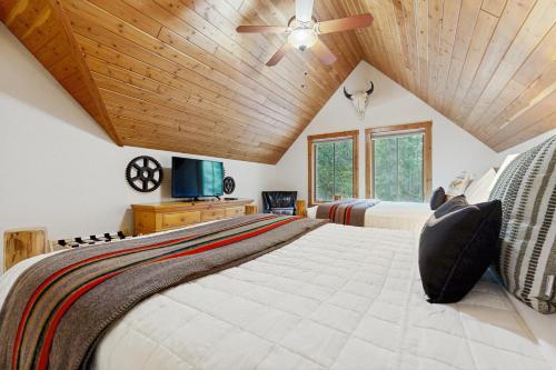 Bear Creek VillageにあるDeer Pine Cabinのベッドが2つあり、天井が木製の寝室