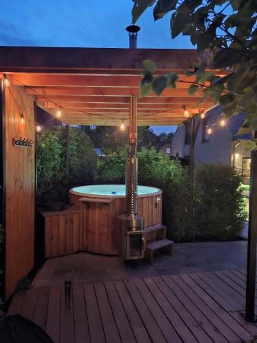 a hot tub under a wooden pergola with a hot tub at Vakantiehoeve 'De Zandrug' in Stekene