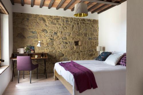 a bedroom with a bed and a stone wall at Palazzo Gramsci in Tatti