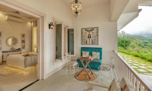 a room with a balcony with a bed and a table at SaffronStays JungleBrooke in Pali