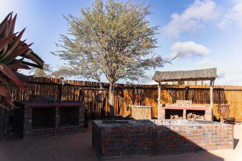 a building with a fireplace and a wooden fence at Loch Maree Guest Farm & Field Camp in Askham