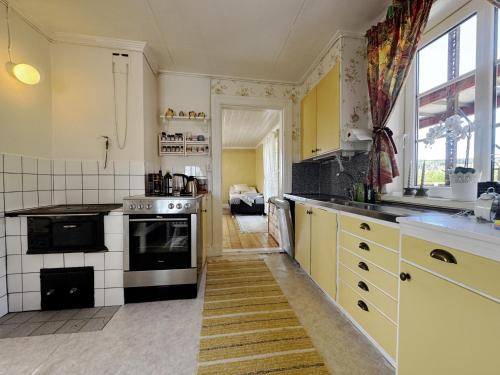 a kitchen with yellow cabinets and a stove top oven at Charming holiday home with views of the landscape and close to Lake Vättern in Hjo