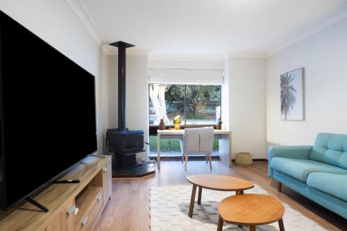 a living room with a tv and a blue couch at Pet Friendly 2BR Family home in Shenton Park in Perth