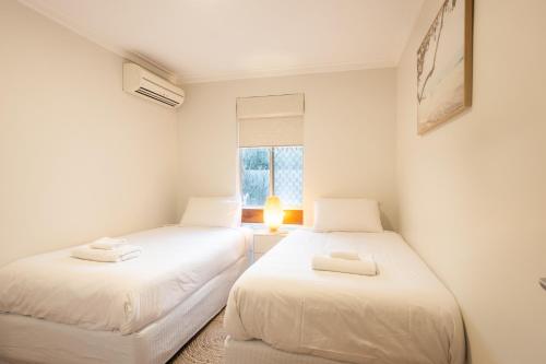two white beds in a room with a window at Pet Friendly 2BR Family home in Shenton Park in Perth