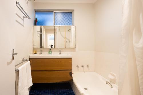 a white bathroom with a tub and a sink and a tubermott at Pet Friendly 2BR Family home in Shenton Park in Perth