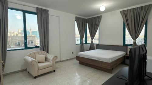 una camera da letto con un letto, una sedia e delle finestre di Karimz Backpackers a Abu Dhabi