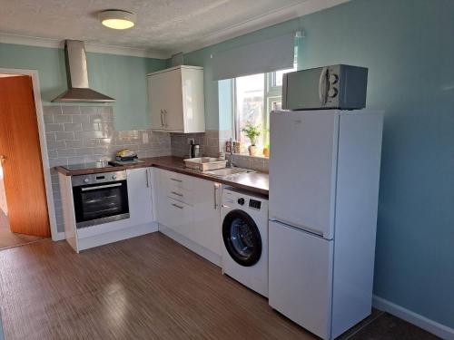 Una cocina con un frigorífico blanco y un lavavajillas. en Skegness, peaceful, bungalow, king bed, parking, en Winthorpe