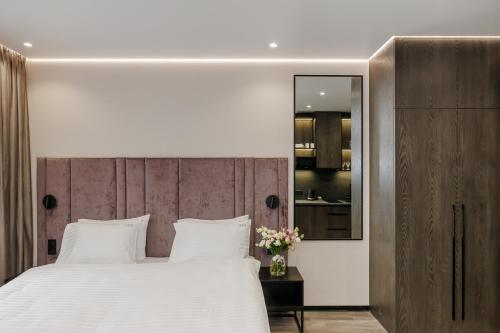 a bedroom with a large white bed and a mirror at Status Apartments in Kyiv