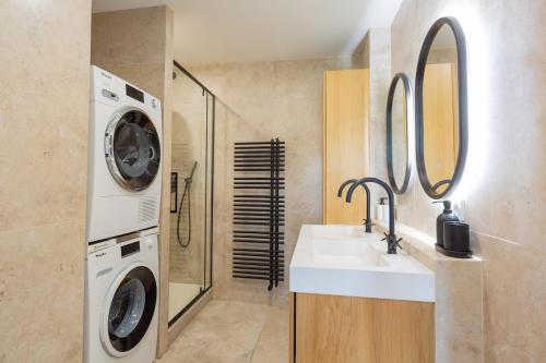 un bagno con lavandino e lavatrice di Art de Recevoir - Prestige & Vue Panoramique sur Saône - Parking Privé T3 Appartement Climatisé a Fontaines-sur-Saône