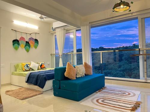 1 dormitorio con sofá azul y ventana grande en Casa Symphony- Hill View Spacious Studio in Baner-Pashan, en Pune