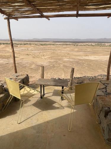 a picnic table and two chairs in the desert at Dunes Clave in Hassilabied