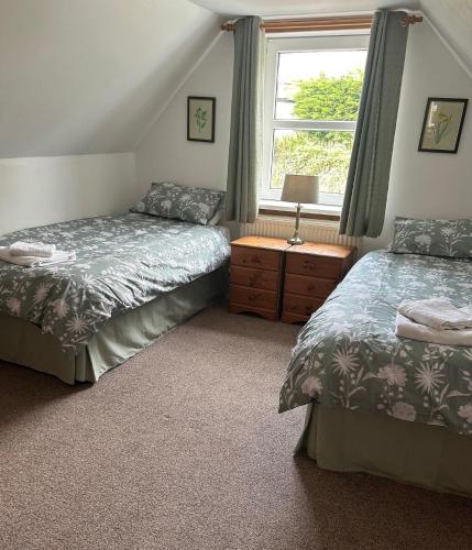 a bedroom with two twin beds and a window at Rowan Cottage in New Galloway