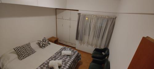 a bedroom with a bed and a chair and a window at Depto Velez Sarsfield in Cipolletti