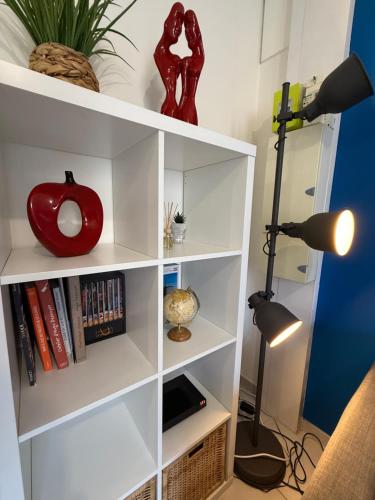 a white book shelf with books and a lamp at Appart' Lumineux & Chic - Parking Rue Sans Stress in Dreux