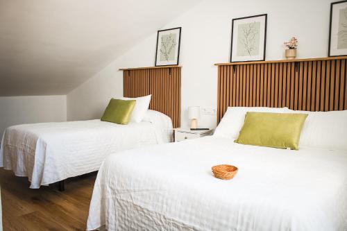 two beds with white sheets and green pillows in a room at Suites Puerta Doñana in Hinojos