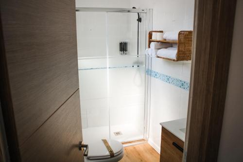 a bathroom with a shower with a toilet and towels at Suites Puerta Doñana in Hinojos
