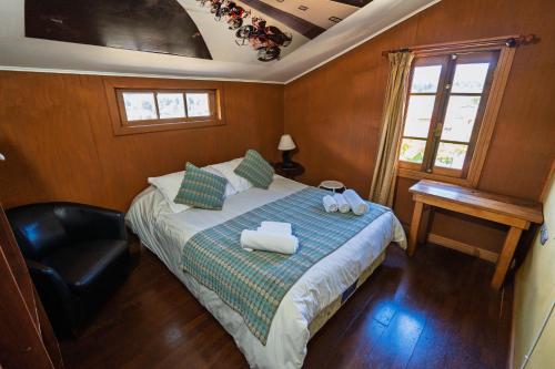 a bedroom with a bed with a chair and a window at Hotel San Giorgio in Capitán Pastene