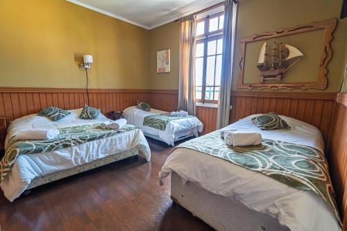 a room with two beds and a mirror at Hotel San Giorgio in Capitán Pastene