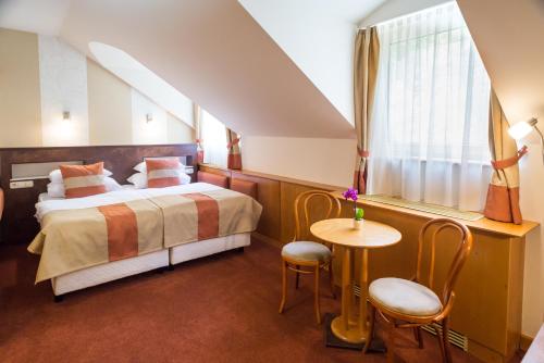 a bedroom with a bed and a table and a window at Hotel Spa Hévíz in Hévíz