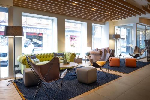a lobby with couches and a table and chairs at voco Bilbao - City by IHG in Bilbao