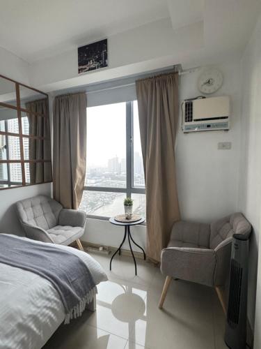 a bedroom with a bed and two chairs and a window at Mi Casa - Cozy Studio with FREE access to Fitness Centre, swimming pool and stunning City View located near the CBD of Ortigas, Makati, BGC in Manila
