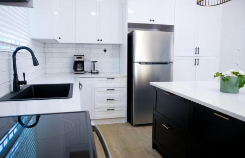 a kitchen with white cabinets and a stainless steel refrigerator at Villa del Nique in Pembroke