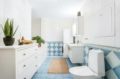 baño con aseo y azulejos azules y blancos en Charming Retro-Modern Apartment in Centrum North, en Tromsø