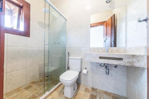 a bathroom with a toilet and a glass shower at Pousada Maré Cheia in Paraty
