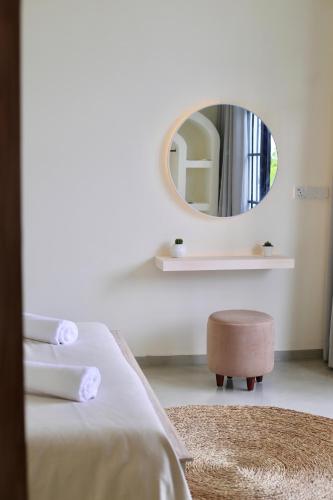 a bedroom with a mirror and a bed and a stool at Māna in Atadahewatugoda