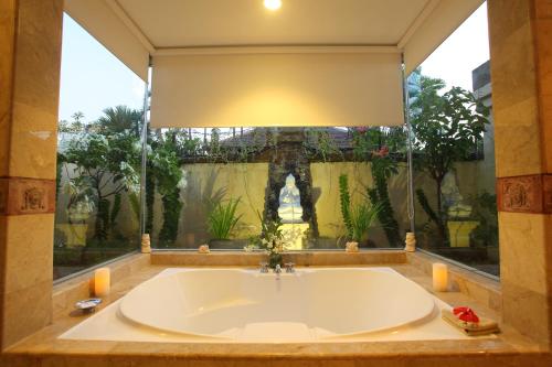 a large bath tub in a room with a large window at Pondok Ayu in Sanur