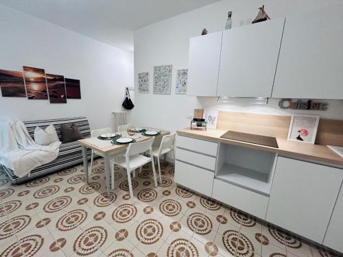 a kitchen with white cabinets and a table and a couch at Angiolieri Flexrent - Immobiliare Abissinia in Riccione