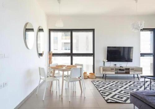 a living room with a table and chairs and a tv at Oַ&O Group- Luxury Apt Tower Best Sea View Bat Yam in Bat Yam