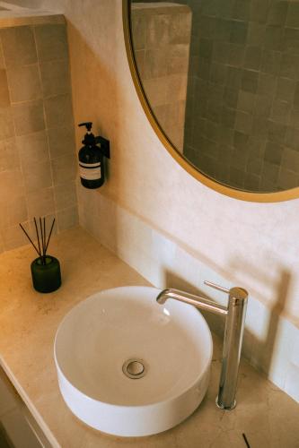 a bathroom sink with a round mirror above it at Flooka Surf & Yoga in Imsouane