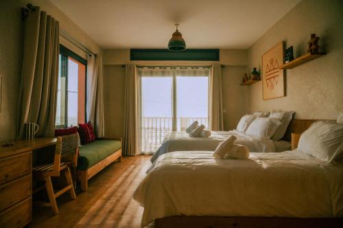 a hotel room with two beds and a window at Flooka Surf & Yoga in Imsouane