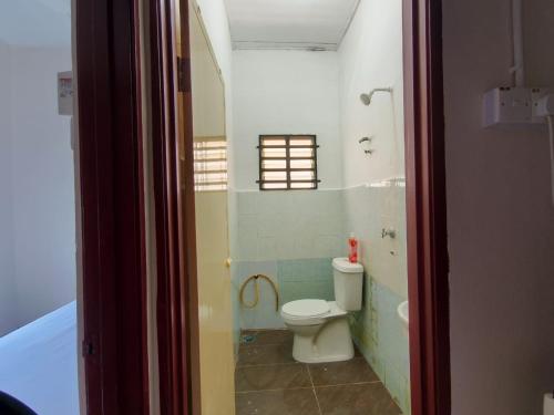 a bathroom with a toilet and a window and a tub at Nariz Homestay Kuala Ketil in Kuala Ketil