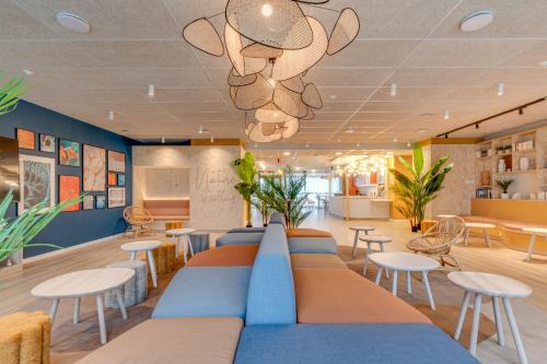 a waiting room with tables and chairs and a chandelier at Sweetly Saclay Gif-sur-Yvette in Gif-sur-Yvette