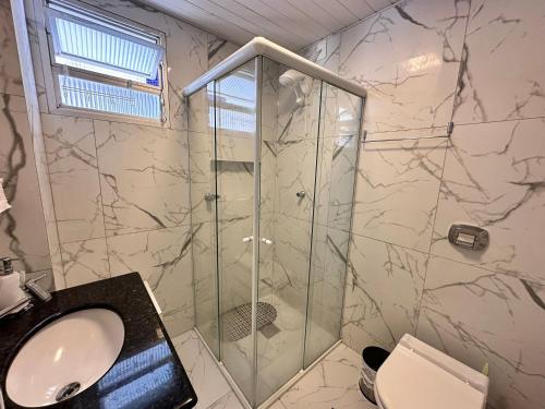 a bathroom with a shower with a sink and a toilet at Apartamento perto de tudo, vista mar, AC quente, Wifi 300mb in Balneário Camboriú