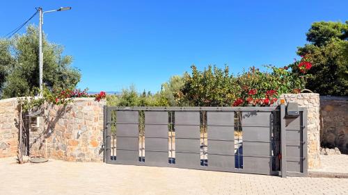 a gate in a stone wall with red flowers at View δύο υπνοδωματιων in Loukísia