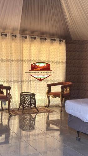 a room with two tables and a bed and curtains at Wadi Rum Nebula, Calm Atmosphere in Wadi Rum